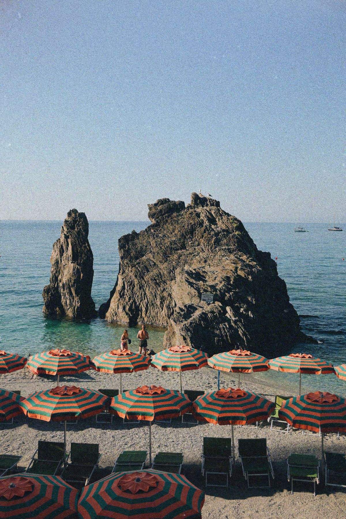 Spiaggia di Monterosso al Mare con ombrelloni a righe fra gli scogli delle Cinque Terre